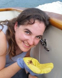 Kelly on a boat holding a tiny squid