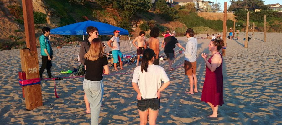 Postdocs talking in a circle on the beach, standing in front of the slack line